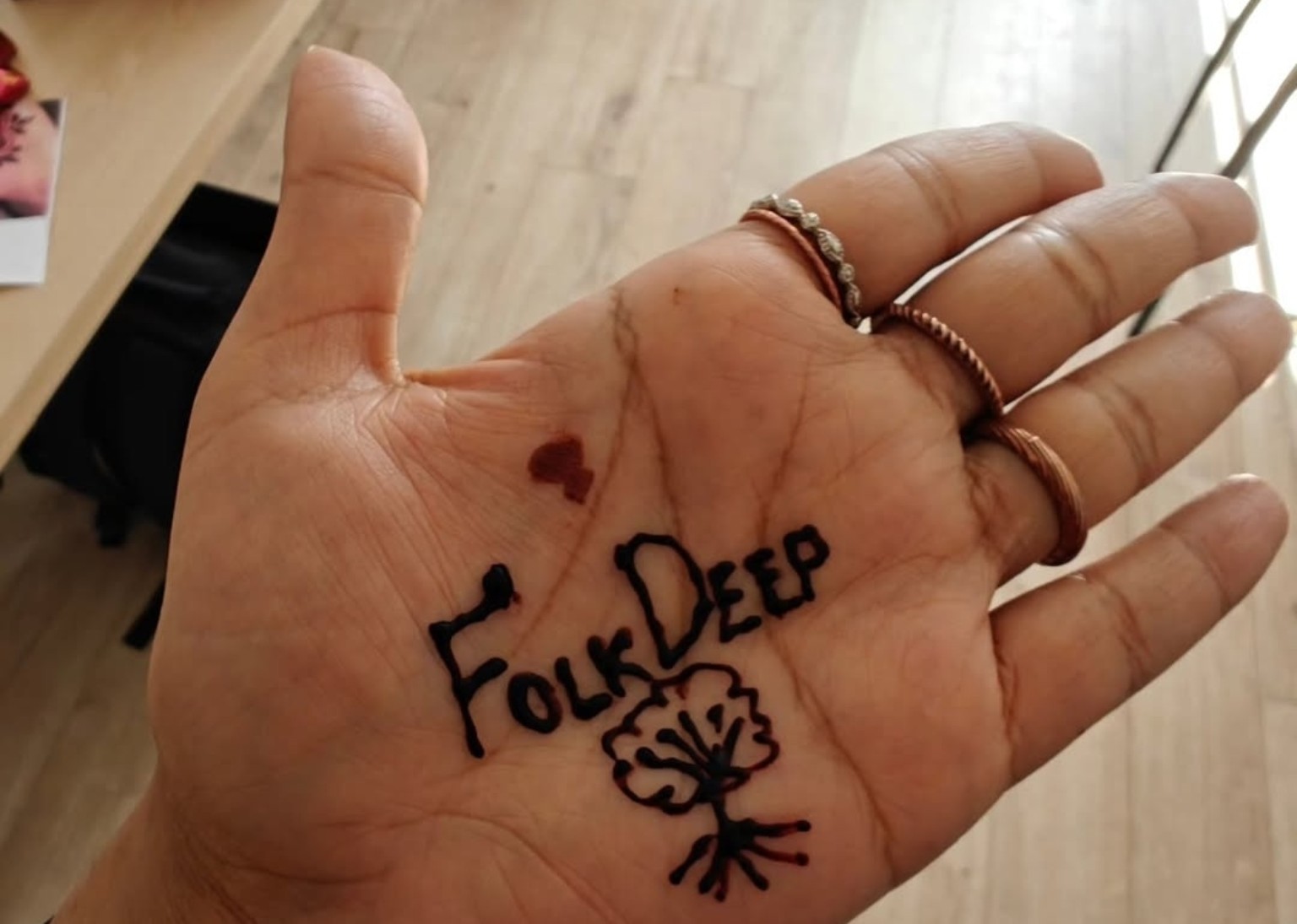 FolkDeep written on a hand with a small flower drawing