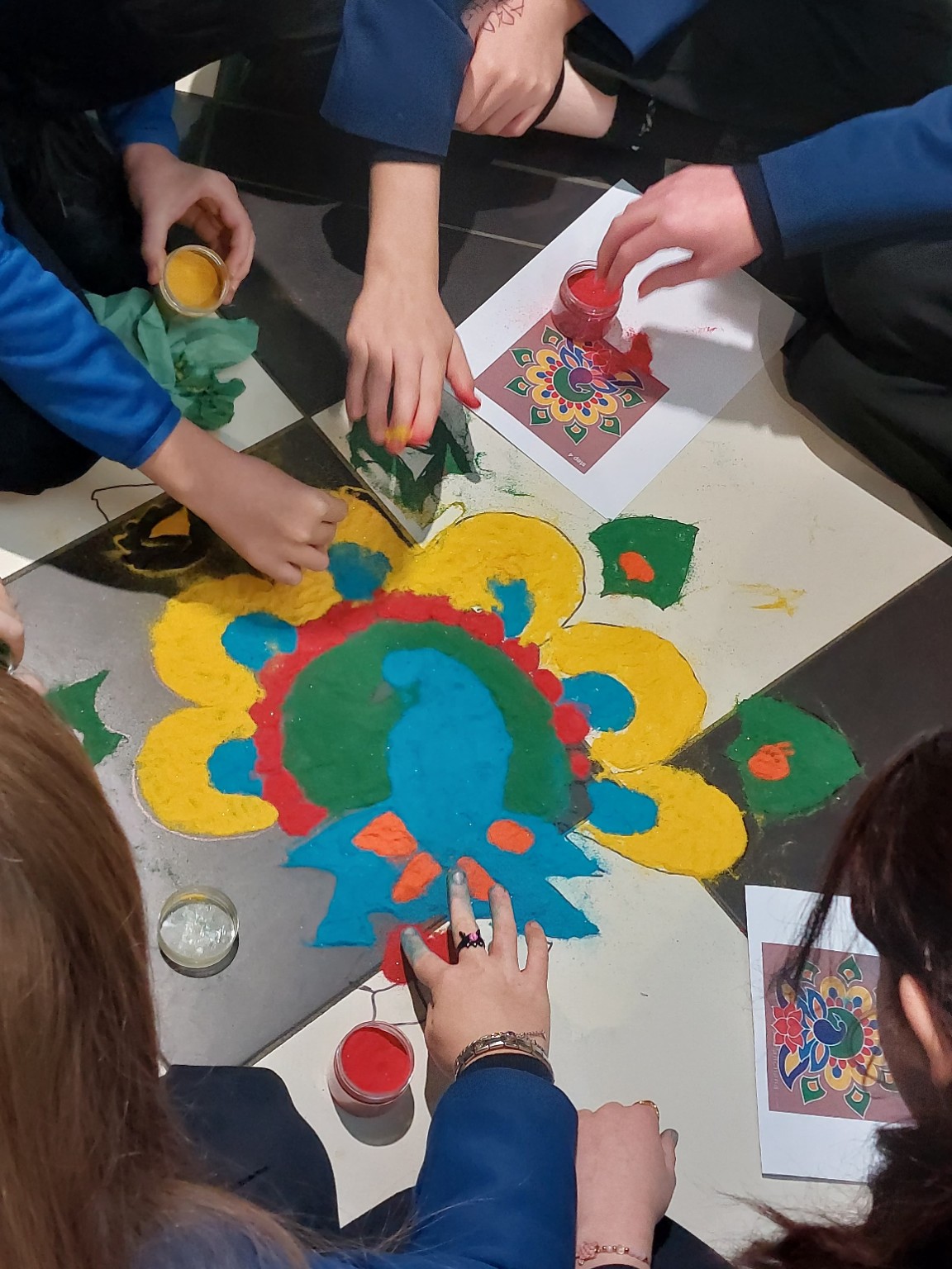 Hands creating colourful folk art with powders
